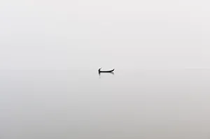 A fishing boat on a perfectly calm Indawgyi Lake in northern Myanmar on a misty afternoon A fishing boat on a perfectly calm Indawgyi Lake in northern Myanmar on a misty afternoon