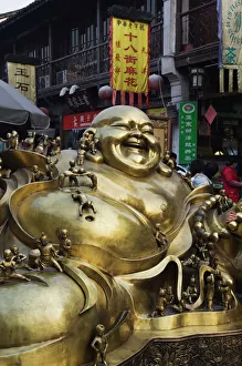 A golden statue of a reclining laughing Buddha covered in small Buddhas A golden statue of a reclining laughing Buddha covered in small Buddhas
