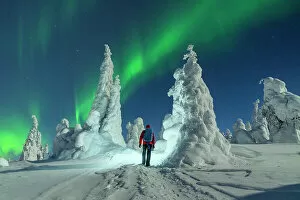 Images Dated 14th November 2022: Hiker with backpack enjoying watching the Northern Lights over frozen trees