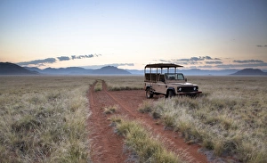 Land rover game vehicle parked by sand road at sunrise, Namib Rand game reserve, Namib Naukluft Park, Namibia, Africa Land rover game vehicle parked by sand road at sunrise, Namib Rand game reserve, Namib Naukluft Park, Namibia, Africa