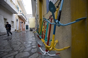 A local man walks past traditional Greek anchors for sale outside a chandlers store A local man walks past traditional Greek anchors for sale outside a chandlers store