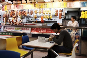 Man in cafe with hanging roast duck and pork and Chinese menus, Hong Kong, China, Asia Man in cafe with hanging roast duck and pork and Chinese menus, Hong Kong, China, Asia