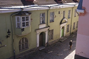 Man with hat in old street with pink and yellow coloured buildings, Tallinn, Estonia, Europe Man with hat in old street with pink and yellow coloured buildings, Tallinn, Estonia, Europe