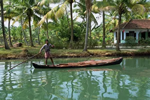Man with pole pushing boat forwards on a Kerala backwater Man with pole pushing boat forwards on a Kerala backwater
