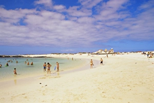 People playing on the beach and natural swimming pool beyond, near El Cotillo People playing on the beach and natural swimming pool beyond, near El Cotillo