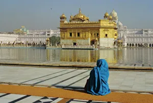 A pilgrim in blue sits by the Holy Pool of Nectar at A pilgrim in blue sits by the Holy Pool of Nectar at