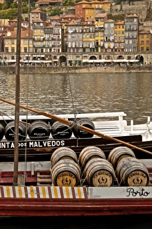 Port wine barrels on a boat on River Douro with Vila Nova de Gaia in the background Port wine barrels on a boat on River Douro with Vila Nova de Gaia in the background