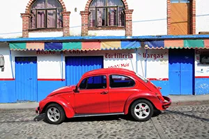 Red Volkswagen Beetle parked on cobblestone street, Tepoztlan, near Mexico City where many city dwellers spend weekends Red Volkswagen Beetle parked on cobblestone street, Tepoztlan, near Mexico City where many city dwellers spend weekends