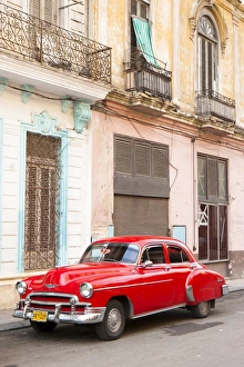 Restrored red American car pakred outside faded Colonial buildings, Havana Restrored red American car pakred outside faded Colonial buildings, Havana