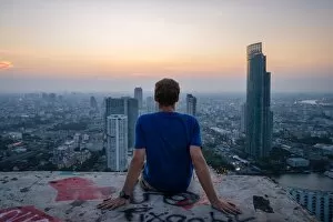 Images Dated 17th April 2015: A single man watching sun set over city skyline at dusk, Bangkok, Thailand, Southeast Asia