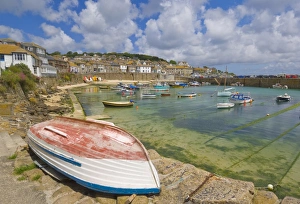 Small unturned boat on the quay and small boats in the enclosed harbour at Mousehole Small unturned boat on the quay and small boats in the enclosed harbour at Mousehole