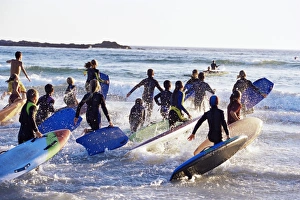 Teenage surfers running with their boards towards the Teenage surfers running with their boards towards the