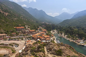 The typical village and harbor of Porto immersed in the green vegetation of the promontory The typical village and harbor of Porto immersed in the green vegetation of the promontory