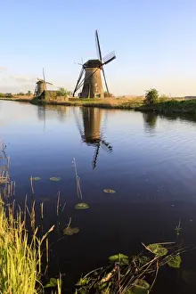 Prints of Typical windmills reflected in the canal framed by grass in spring, Kinderdijk, UNESCO World Heritage Site, Molenwaard, South Holland, The Netherlands, Europe Images Dated 2017 April: Typical Windmills Print, Kinderdijk Canal Reflection
