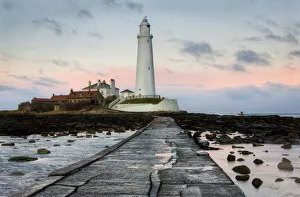 View along the tidal causeway to St. Marys Island and St. Marys Lighthouse at dusk View along the tidal causeway to St. Marys Island and St. Marys Lighthouse at dusk