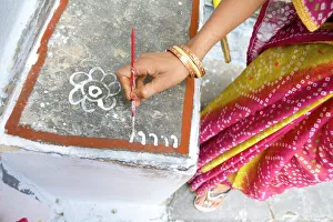 Woman painting her doorstep with rice flour paste, making rangoli design Diwali Festival decorations, Udaipur Woman painting her doorstep with rice flour paste, making rangoli design Diwali Festival decorations, Udaipur