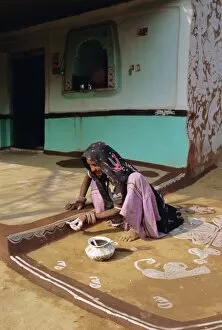 Adorning Collection: Woman painting the wall of a village house