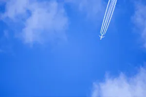 An airplane flies across a blue sky leaving vapour trails An airplane flies across a blue sky leaving vapour trails