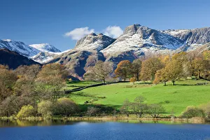 Autumn colours beside Loughrigg Tarn with views to the snow dusted mountains of the Langdale Pikes Autumn colours beside Loughrigg Tarn with views to the snow dusted mountains of the Langdale Pikes