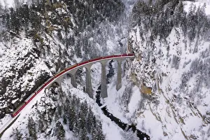Bernina Express passes through the snowy woods Filisur Canton of Grisons Switzerland Bernina Express passes through the snowy woods Filisur Canton of Grisons Switzerland