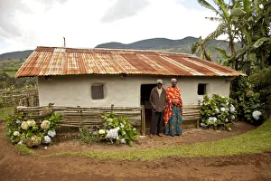 Burundi. A couple outside a traditional house on their farm Burundi. A couple outside a traditional house on their farm