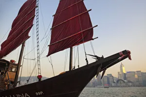 China, Hong Kong, Kowloon, Victoria Harbour, Junk Boat Sail and City Skyline in Background China, Hong Kong, Kowloon, Victoria Harbour, Junk Boat Sail and City Skyline in Background