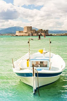 Close up of a boat docked in the Nafplio harbour and Bourtzi fortress in the background Close up of a boat docked in the Nafplio harbour and Bourtzi fortress in the background