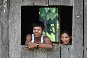 Couple looking out of window in the Amacayon Indian Village, Amazon river, Puerto Narino Couple looking out of window in the Amacayon Indian Village, Amazon river, Puerto Narino