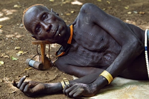 An elder of the Karo tribe rests with his head on his An elder of the Karo tribe rests with his head on his