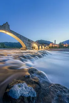 Devils Bridge Collection: Europe, Italy, Emilia Romagna: Bobbio, falls on the Trebbia river and the medieval town at twilight