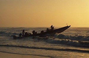 Fishermen launch their boat into the Atlantic Ocean at sunset Fishermen launch their boat into the Atlantic Ocean at sunset