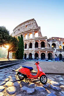 Italy, Rome, a red Vespa motorbike in front of Colosseum at sunrise Italy, Rome, a red Vespa motorbike in front of Colosseum at sunrise