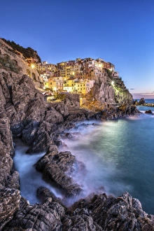 Manarola village illuminated by the blue light of dusk with its typical pastel colored houses Manarola village illuminated by the blue light of dusk with its typical pastel colored houses