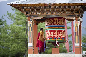 A monk and a prayer wheel on the path to the Paro Taktsang monastary in the Himalayan A monk and a prayer wheel on the path to the Paro Taktsang monastary in the Himalayan