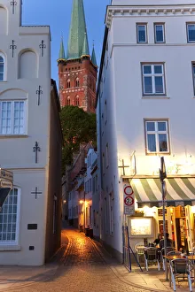 Narrow street to St Petri Church & cafe restaurant at dusk, Lubeck, Germany Narrow street to St Petri Church & cafe restaurant at dusk, Lubeck, Germany