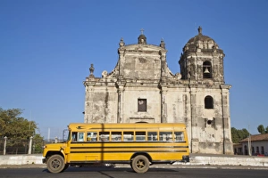 Nicaragua, Leon, American yellow bluebird bus driving past San Juan Church Nicaragua, Leon, American yellow bluebird bus driving past San Juan Church