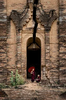 Two novice monks at the entrance to the unfinished Pahtodawgyi pagoda known for a crack Two novice monks at the entrance to the unfinished Pahtodawgyi pagoda known for a crack