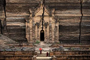 Two novice monks walking towards unfinished Pahtodawgyi pagoda known for a crack caused Two novice monks walking towards unfinished Pahtodawgyi pagoda known for a crack caused