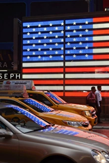 People walking past Neon sign of American Flag on Times Square, New York, Manhattan, USA People walking past Neon sign of American Flag on Times Square, New York, Manhattan, USA