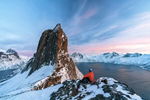 Q3 2023 Collection: One person contemplating the sky at sunset sitting on a snowy ridge on Segla mountain, Senja
