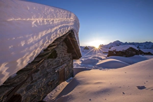 The last rays of sun light up the Prabello alp chalets covered with snow The last rays of sun light up the Prabello alp chalets covered with snow