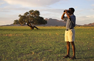 A safari guide scans the horizon with his binoculars A safari guide scans the horizon with his binoculars