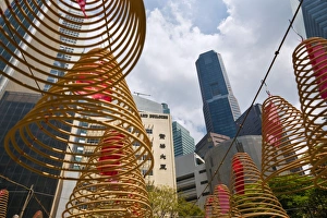 Singapore, Singapore, Raffles Place. Spiral incense coils with city skyline in background at Wak Hai Cheng Singapore, Singapore, Raffles Place. Spiral incense coils with city skyline in background at Wak Hai Cheng