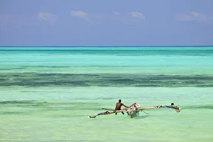 Tanzania, Zanzibar, Unguja, Jambiani. A man sits on his boat near the shore Tanzania, Zanzibar, Unguja, Jambiani. A man sits on his boat near the shore