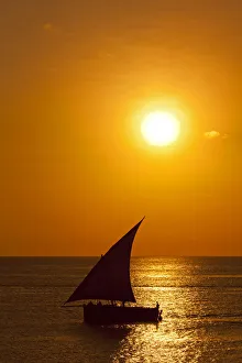 Tanzania, Zanzibar, Unguja, Stone Town. A Dhow sails out of the harbour at sunset Tanzania, Zanzibar, Unguja, Stone Town. A Dhow sails out of the harbour at sunset