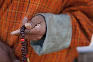Wangdue, Bhutan. A man in a Gho with a closeup of Bhuddist prayer beads Wangdue, Bhutan. A man in a Gho with a closeup of Bhuddist prayer beads