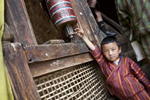 A young boy playing with a prayer wheel in the Thangbi Mani monastery in Bhutan A young boy playing with a prayer wheel in the Thangbi Mani monastery in Bhutan