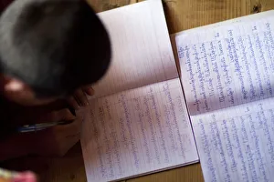A young monk studying and writing sanskrit at the monastery in Thimpu Bhutan A young monk studying and writing sanskrit at the monastery in Thimpu Bhutan