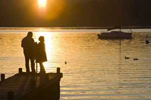 A couple on a jetty at sunset at Waterhead Ambleside UK A couple on a jetty at sunset at Waterhead Ambleside UK