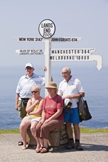 Friends on holiday having their photo taken at Lands End with the distance to the town where they live Friends on holiday having their photo taken at Lands End with the distance to the town where they live